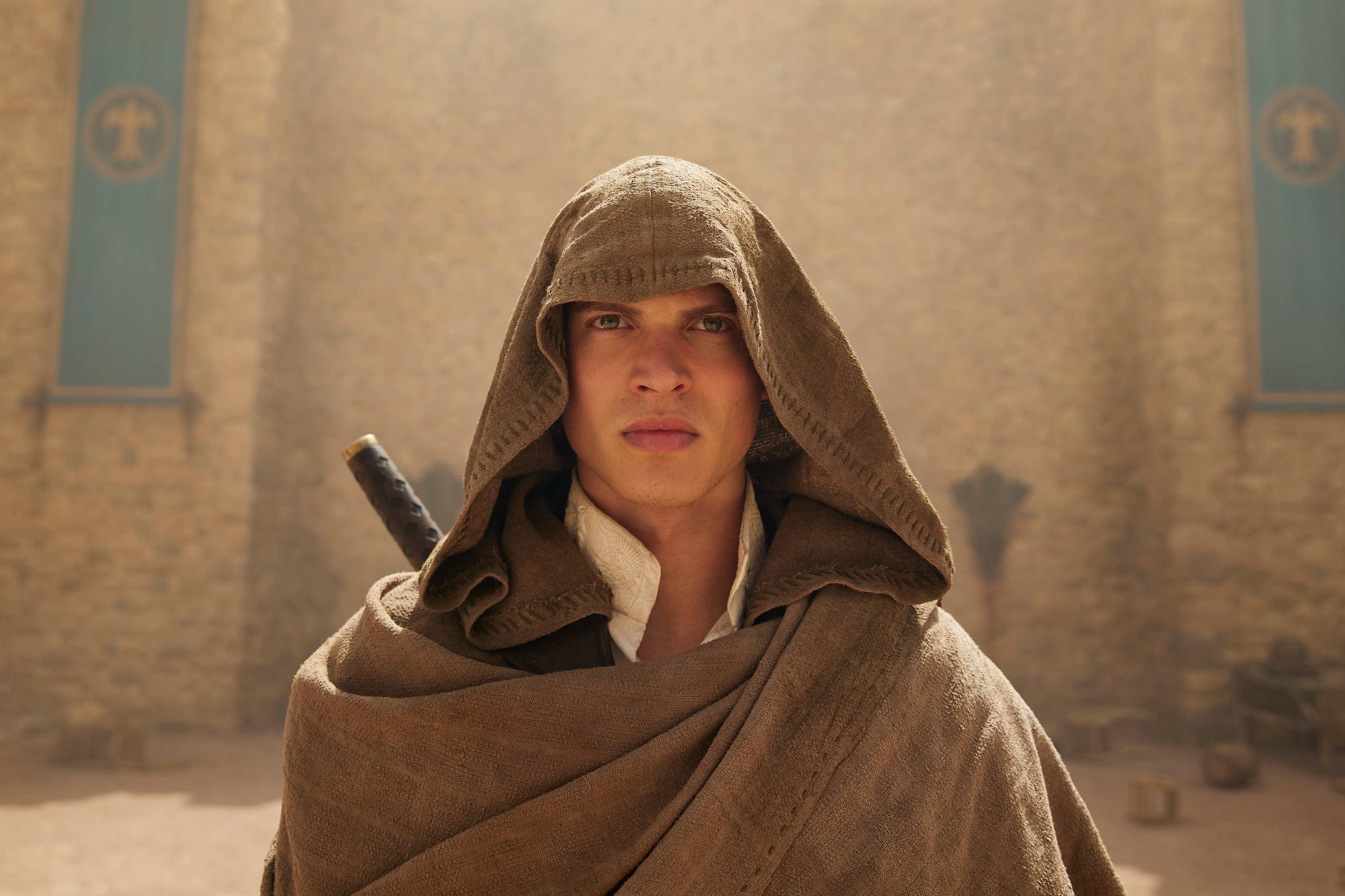 Medium close up of Rand. A brown woven cloak is draped around his head and body.