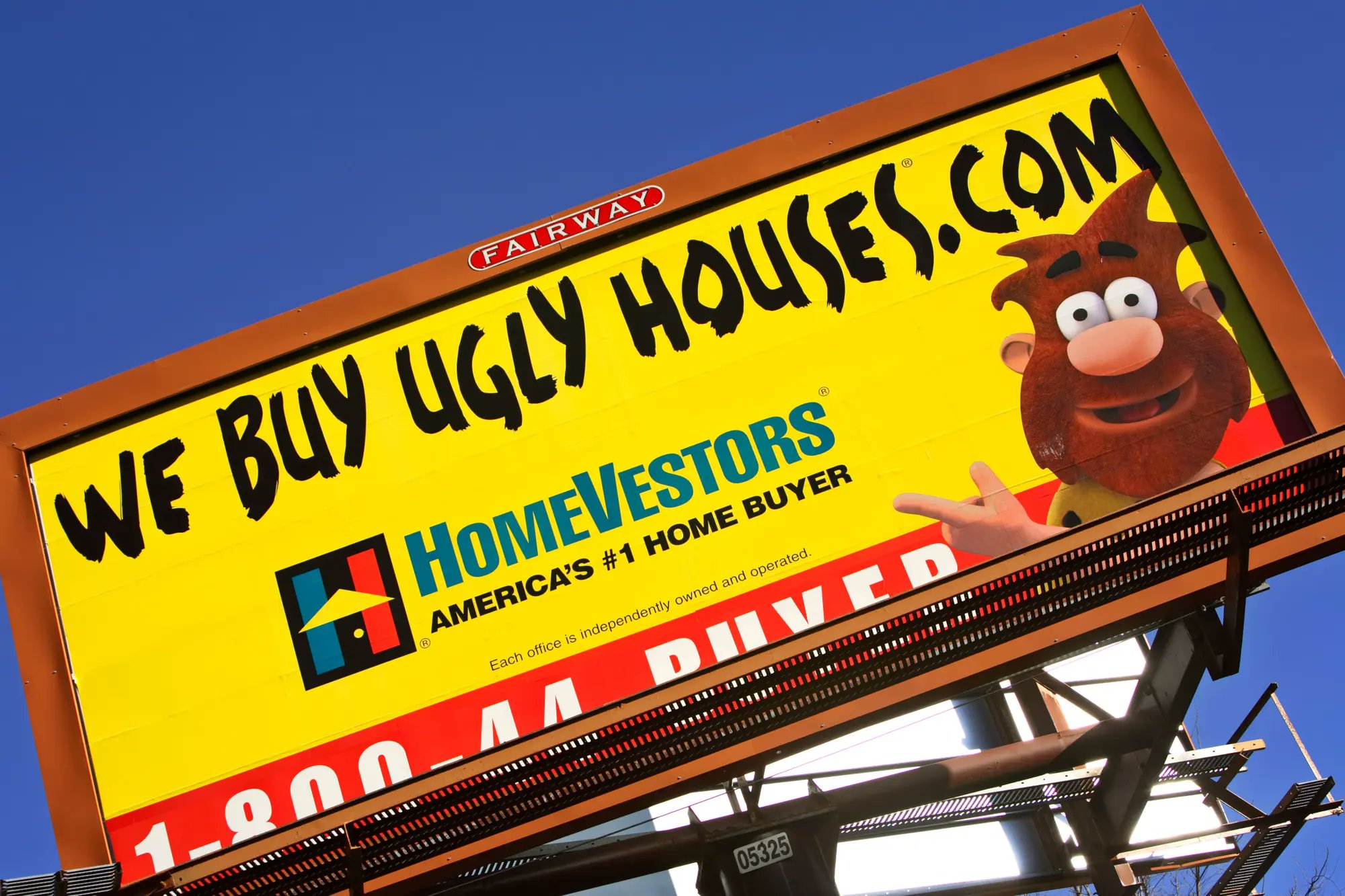 Photo of a billboard for HomeVestors. The company's logo and slogan, "America's #1 Home Buyer" appear under the URL WeBuyUglyHouses.com and above a 1-800 phone number. To the right of the logo is the company's cartoon mascot, a "caveman" named Ug.