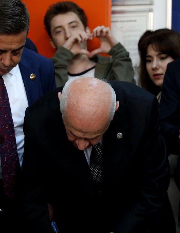 Devlet Bahçeli oy kullanırken bir genç arkasında kalp yaptı.