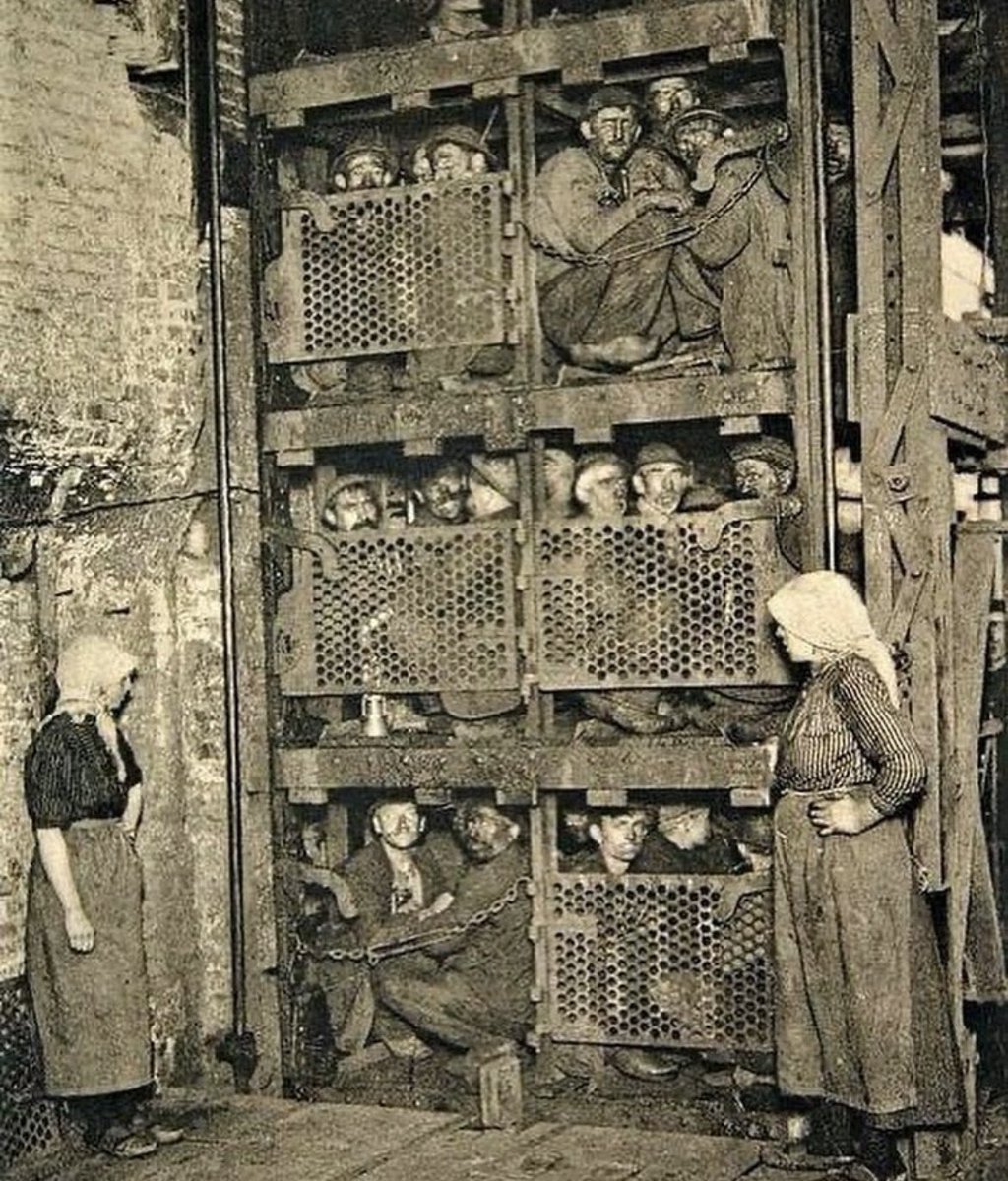 Coal miners in Belgium crammed in a mine elevator coming up after a long days work in 1900.