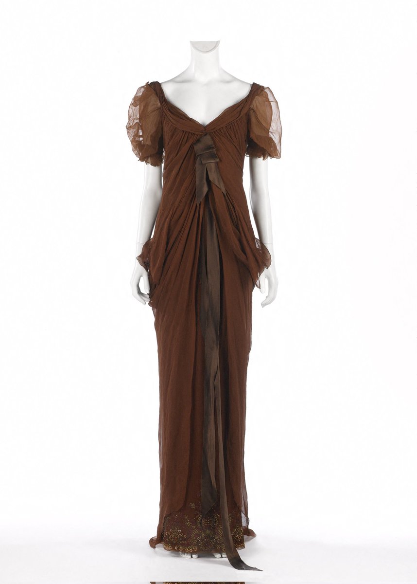 French fashion designer Christian Lacroix was born #OnThisDay in 1951. He designed this draped mahogany-toned silk chiffon gown, embellished with long brown silk satin ribbon and beaded embroidery, for his A/W 2006 Haute couture collection @PalaisGalliera #fashiondesigner #dress
