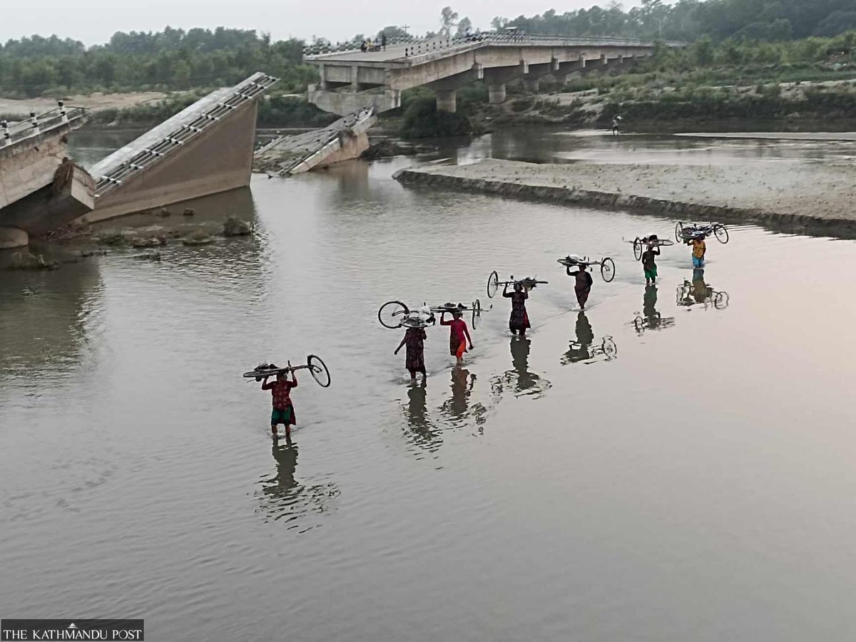 kathmandupost's tweet photo. Women with bicycles on their heads ford the Babai river at Jabdhighat in Bardiya in this recent photo. The bridge, built by Pappu Construction, was damaged before it was handed over to the authorities five years ago and was destroyed in last year’s floods.

Photo by: Kamal Panthi https://t.co/Die32DKnOA