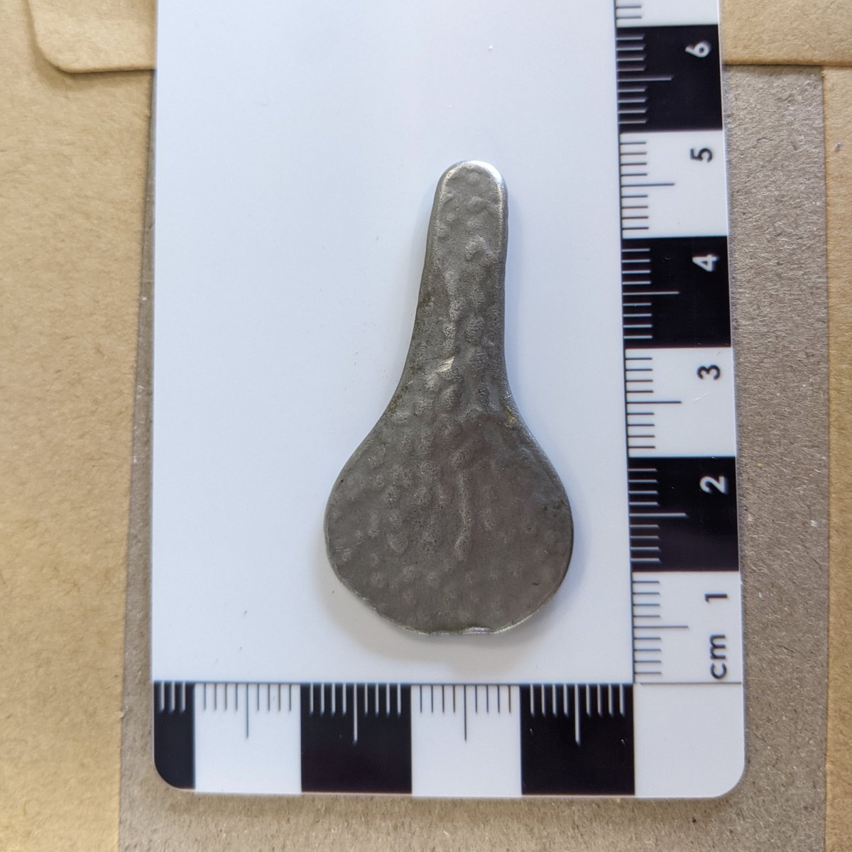 WritingRemains's tweet photo. I need a hand ID-ing his metal detectorist find. It's shaped like a tiny bike seat or tennis racket, flat not concave. Hammered or dappled finish. Probably modern? Something obvious? Help! 🙏 https://t.co/1Xor9KXecj