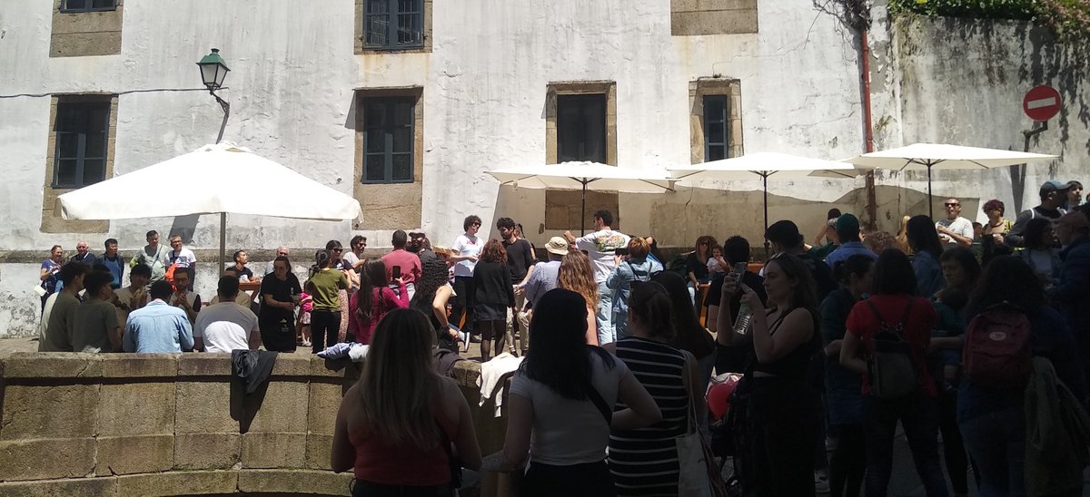 Hoxe Galicia celebra o #DíaDasLetrasGalegas. Agora fixádevos na foto: a dereita (e case nas sombras) a xente mira cara ao centro onde un grupiño de xente baila mentras, a esquerda, os pandereterios de <a href="/CantigaseAgarim/">Cantigas e Agarimos</a> (baixo o parasol) tocan unhas cantas ❤️❤️❤️