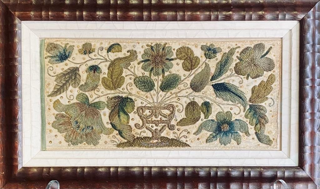 Here is the seventeenth-century embroidered picture in all of its glory! The stitcher, who was perhaps a professional embroiderer, used metal purl in a variety of colours to craft an ornate vase and floral arrangement. In between the flowers and leaves are gold spangles ✨