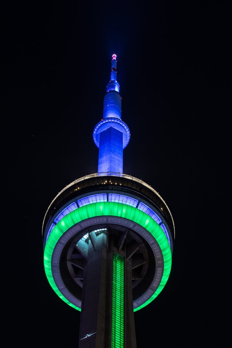 closeup of the CN Tower at night lit blue and green / gros plan de la Tour CN de nuit éclairée en bleu et vert