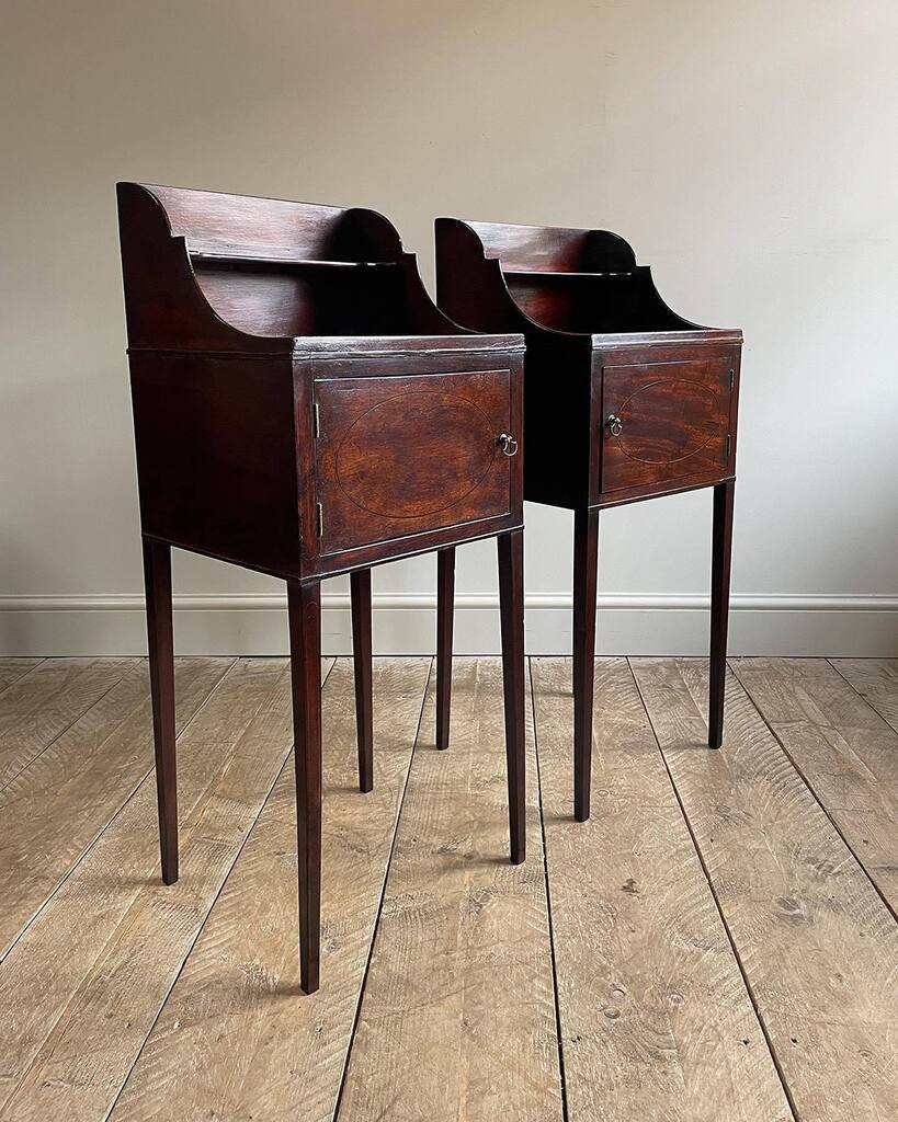 A pair … yes, a PAIR… of exceptionally elegant Georgian mahogany pot cupboards. Raised gallery tops with shelves, over doors inlaid with decorative oval panels and boxwood line fitted with brass axehead handles. Raised on slender tapered legs. Circa.… instagr.am/p/CsbbPL2IRkq/