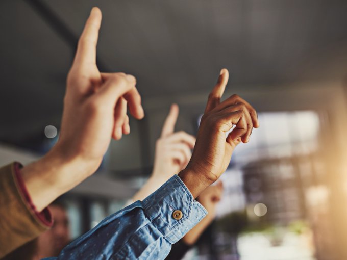 A photo of three hands raised waiting to ask a question.