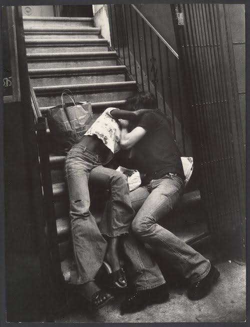 Couple kissing on building steps , 1970s.