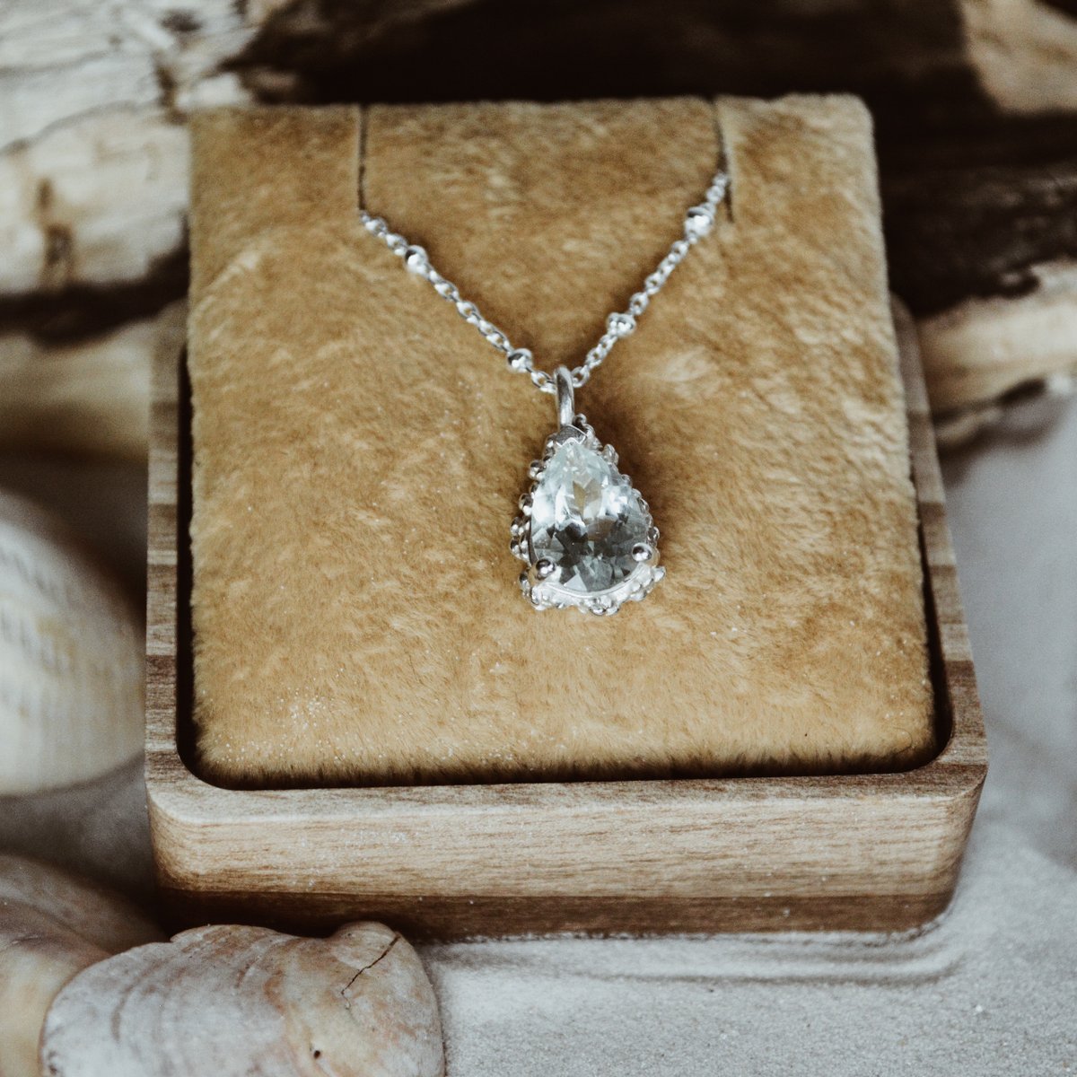 The Alba necklace with the ocean-colored gemstone, which glistens with different shades of blue and green in the sunlight, is sure to add a touch of sophistication to any outfit.