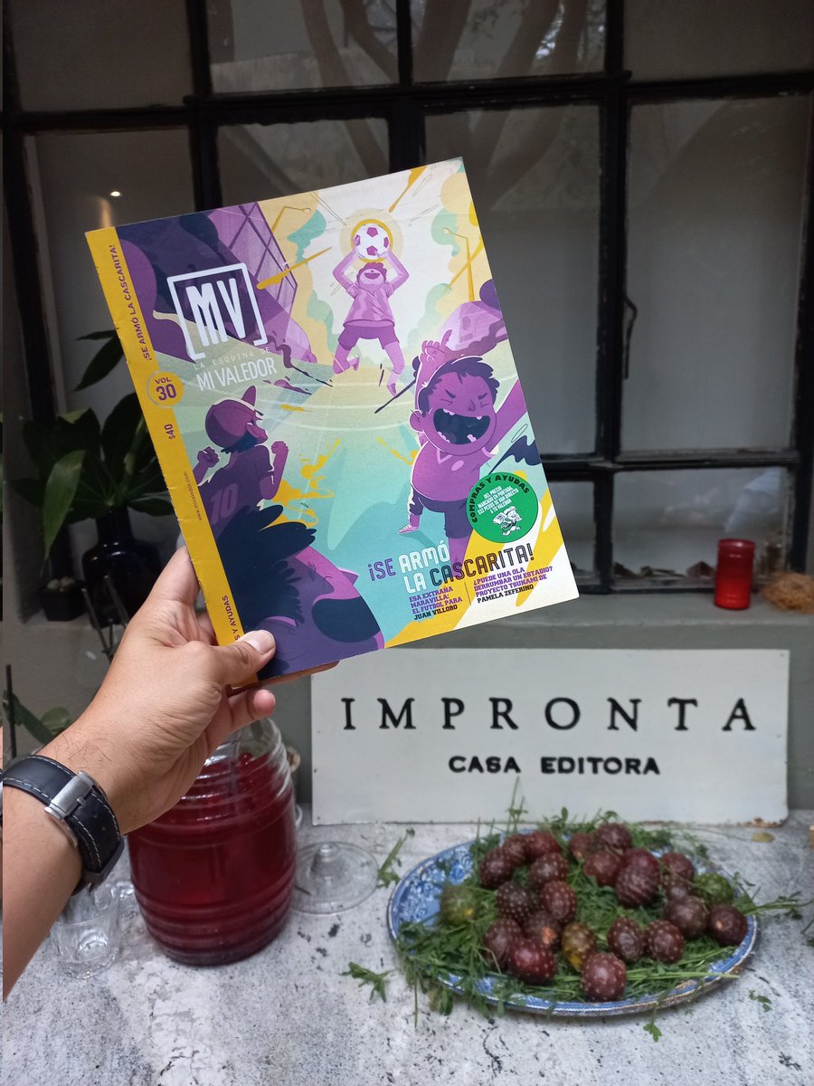 Mi Valedor frente al letrero de Impronta Casa Editora y una mesa con un plato de pitayas.