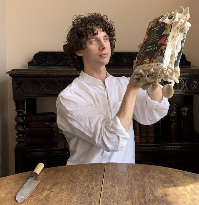 smithsonian's tweet photo. This is a scientist who's about to eat his words. And his mushrooms.  

Biologist Merlin Sheldrake studied fungi at our @stri_panama. He dipped a copy of his book about fungi into mushroom spores, sautéed them in butter and ate them.  

Bon appétit. https://t.co/M2Z5GyMyzX https://t.co/SDUqws2wb4