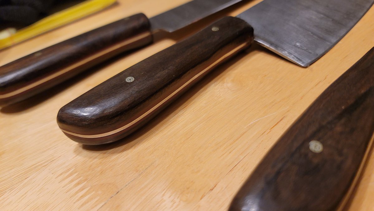 OfficialFarEm's tweet photo. I've been making knives recently. Here's a 6 piece kitchen knife set with leather/canvas chef's roll. Knives are high carbon ladder damascus with Ziricote handles and Red Micarta spacers. Client requested that they be "rustic" so some tooling marks were left intentionally. https://t.co/Sv5aLxT9vw