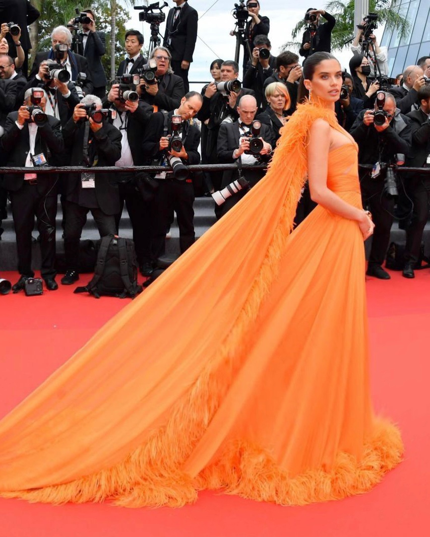 #SaraSampaio attends the 76th Cannes Film Festival Monster Premiere in a sun orange draped chiffon gown with feathered trim from the #ZMCouture Spring-Summer 2023 Couture Collection. #ZuhairMurad