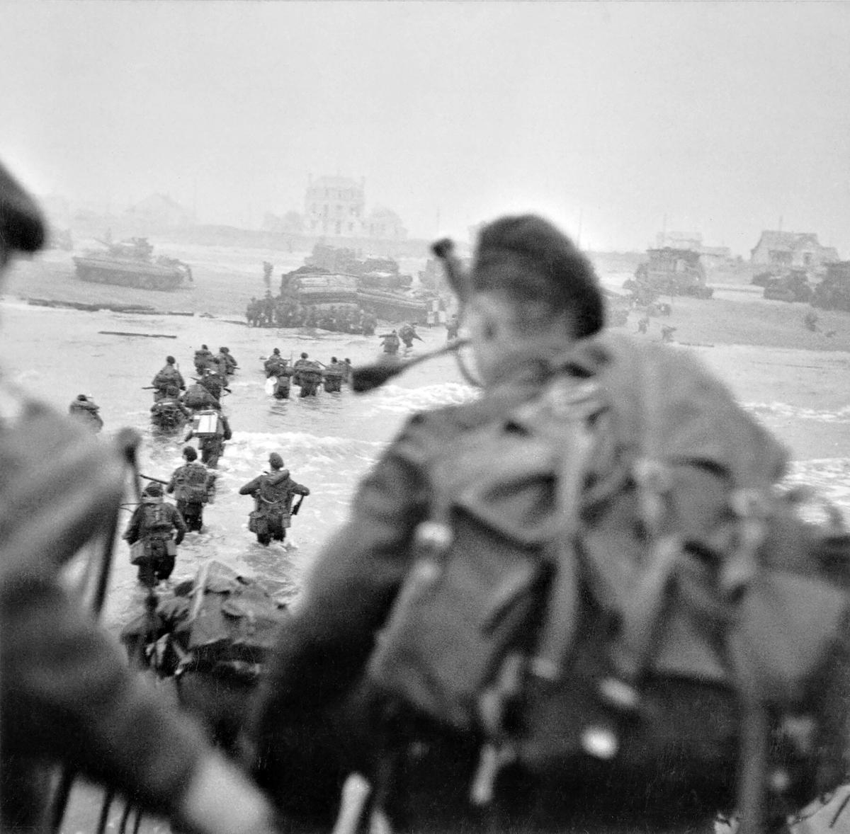 Commandos of 1st Special Service Brigade led by Brigadier Lord Lovat (in the water, to the right of his men) land on Queen Red beach, Sword area, circa 08:40 hours, 6 June 1944. Lovat's piper, Bill Millin, is in the foreground about to disembark.