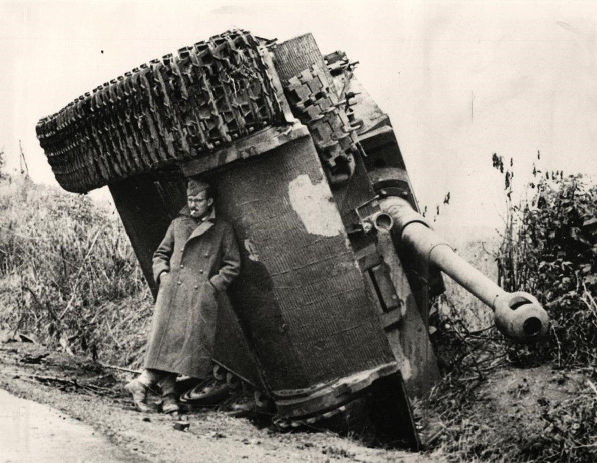 Historycord's tweet photo. A British soldier hiding from the rain under an overturned Tiger tank. Italy, 1944. #History https://t.co/YCIvfE7TIg