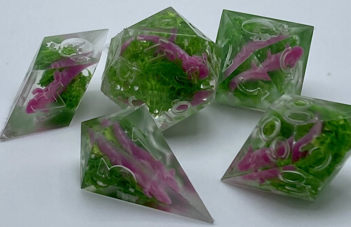 oddduckdice's tweet photo. I need to repair the last three dice in this set. HOWEVER, too pumped not to share. This set, when finished, will be my next giveaway. I’m eyeballing early June. Tiny resin axolotol in green moss. #dice #dicemaker #ttrpg #ttrpgdice #axolotol https://t.co/10cSSjRFad
