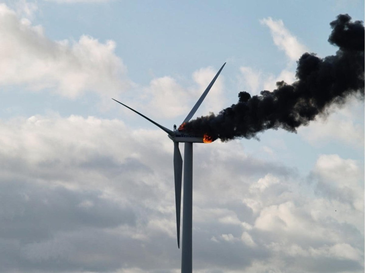 Photo of two engineers hugging on top of a wind turbine that’s on fire. Their only escape route became blocked. One worker jumped off the turbine, the other burned to death.