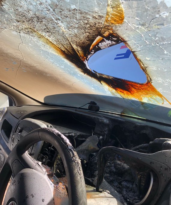 The burnt out inside of a car with hole in the windscreen where sunlight has caught