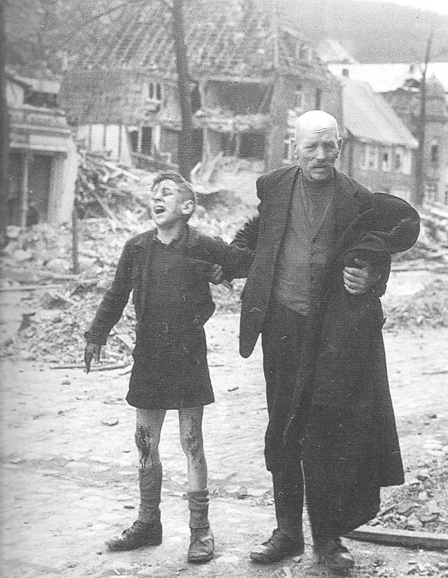 A bloodied young boy screams out in the ruins of his neighborhood after it was bombed, Germany, 1945