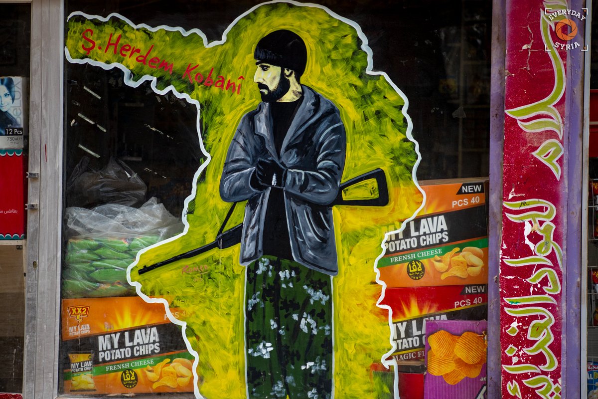 EverydaySyria's tweet photo. A mural of Musa Herdem, a prolific sniper from Iranian Kurdistan, is displayed on a shop window in #Kobani. Herdem was well known for his participation in the defense of Kobani as part of the #YPG, and was killed in battle on April 7, 2015, the day the city center was liberated. https://t.co/zzpU4K7Ugn