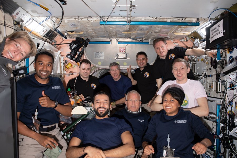 Ten astronauts, cosmonauts and private astronauts float in a crowded module aboard the International Space Station. The space travelers are smiling at the camera, with one giving a thumbs-up; most are wearing dark navy shirts or black polos. The four members of Axiom Mission 2—Peggy Whitson, Ali Alqarni, John Shoffner, and Rayyanah Barnawi—are near the front of the photo. Credit: NASA