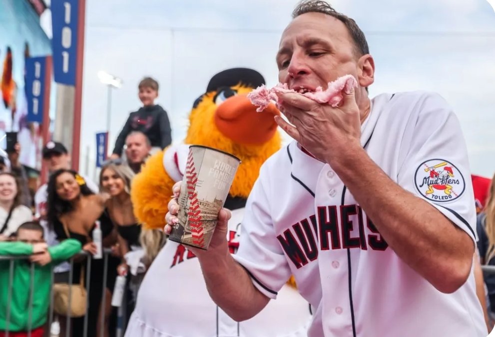 this photo of Joey Chestnut looks like if you typed 'Eating Cotton Candy at a Minor League Baseball Game' into an AI