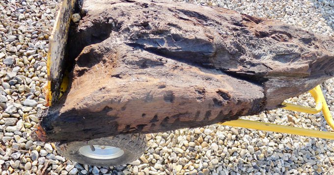 A photograph of a decoratively carved piece of wood laid on a trolley. 