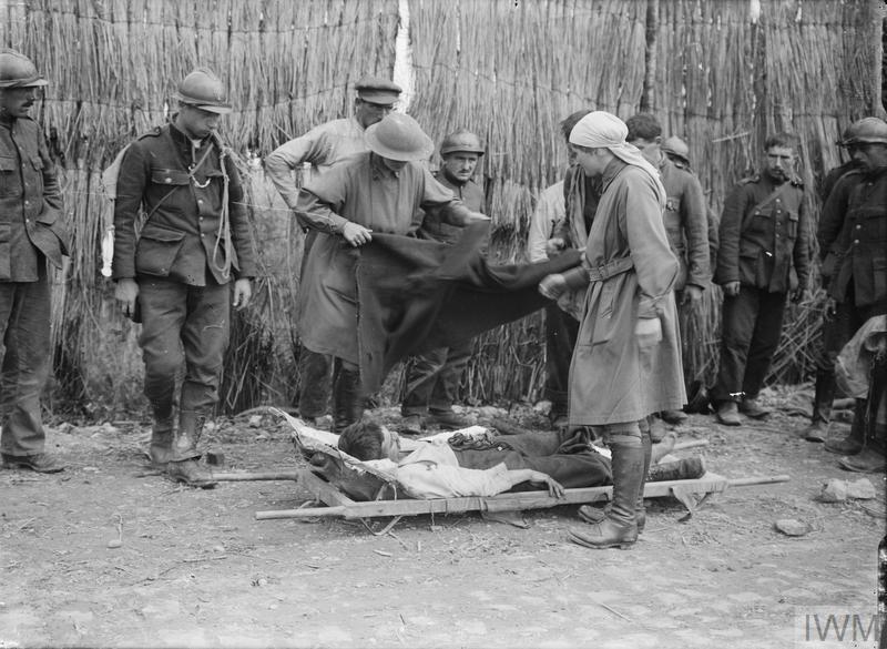 📷 - Baroness Elizabeth de T'Serclaes and Mairi Chisholm treat a wounded Belgian soldier in a street shrouded by a screen at Ramscapelle, Belgium, on 11 September 1917. © IWM Q 2963