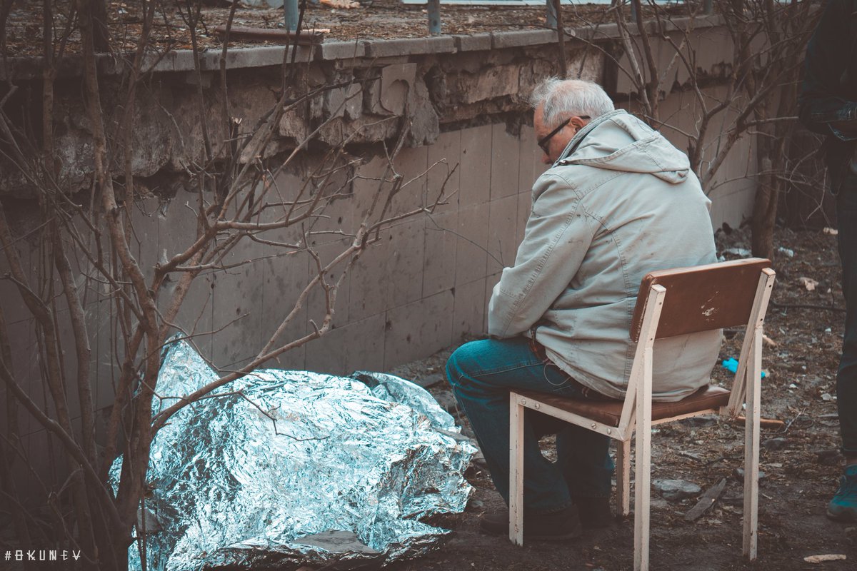 This man first squatted for several hours, then a chair was found for him. 
Under a thin layer of foil lays a  body of his nine-year-old granddaughter, who was killed by a russian missile. The girl lived almost all her life under the conditions of Russian aggression.
@Okunev64