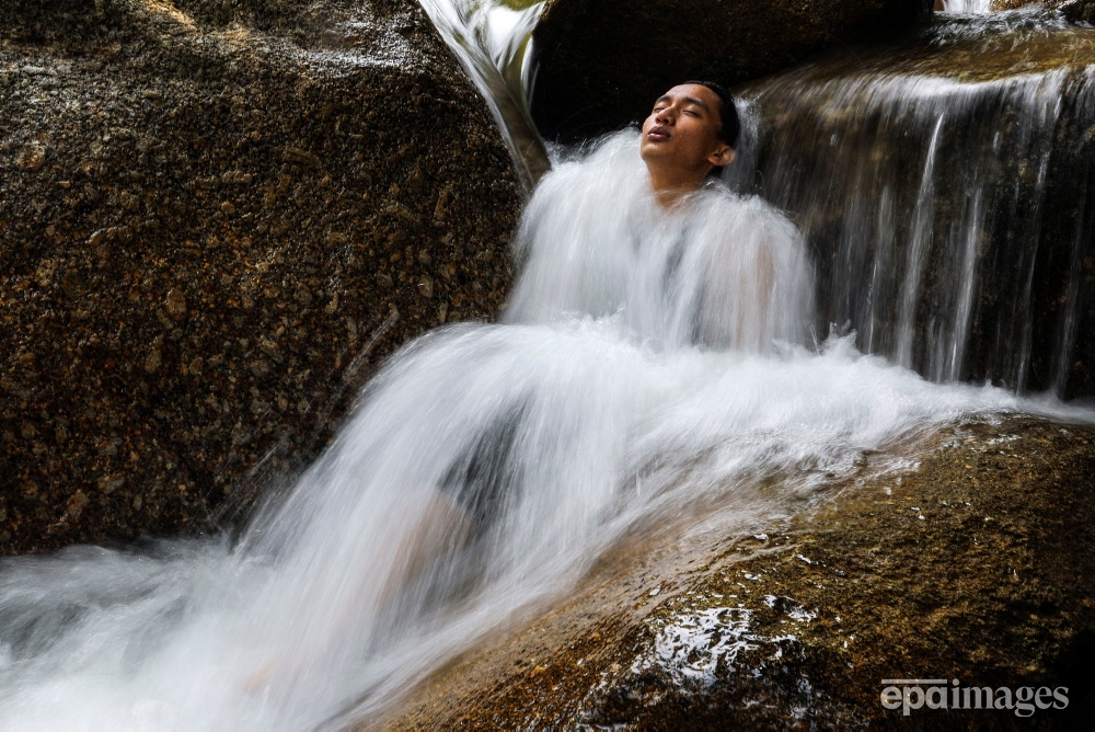 An image made with a slow shutter speed shows a man cooling off in a small waterfall of the Kalumpang River during a hot day with up to 33 degrees Celsius, in Tanjung Malim, Malaysia, 02 June 2023.  📸 EPA / Fazry Ismail 

#heatwave #Malaysia #Waterfall #epaimages