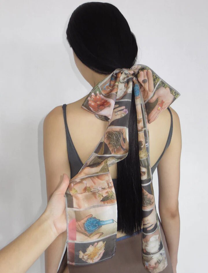 silk scarf featuring photographs of hands holding things by paloma wool