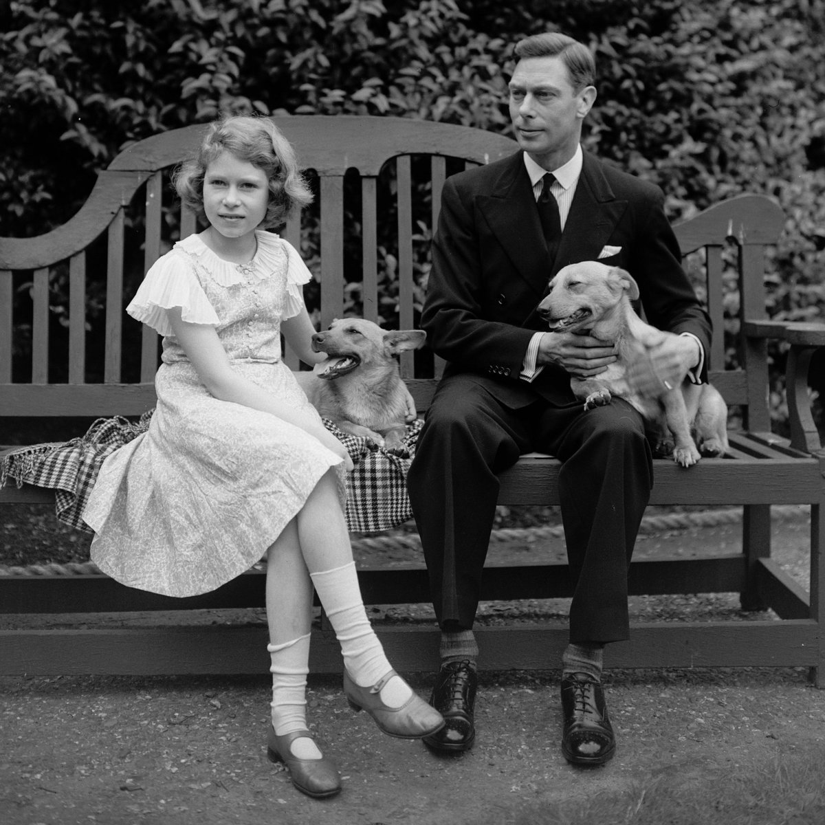 Our late Queen, Elizabeth II, with her father - King George VI - and her first two corgis.

The photograph was taken in July 1936, when she was a young Princess and her father was the Duke of York. 

Her father would become King-Emperor less than half a year later.