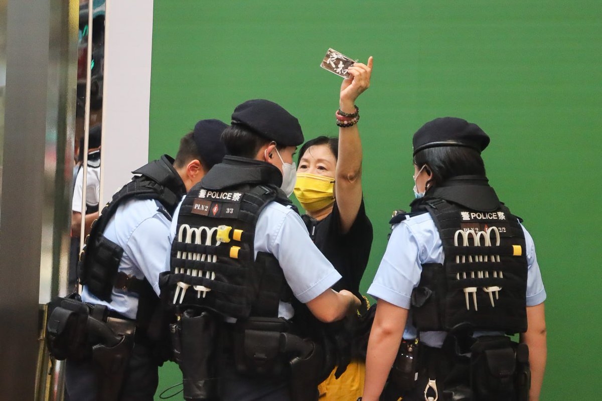 These two women were taken away by police from near the Sogo Department  Store in Causeway Bay around 3:45pm. The one, while surrounded by police,  holds up a small piece of paper