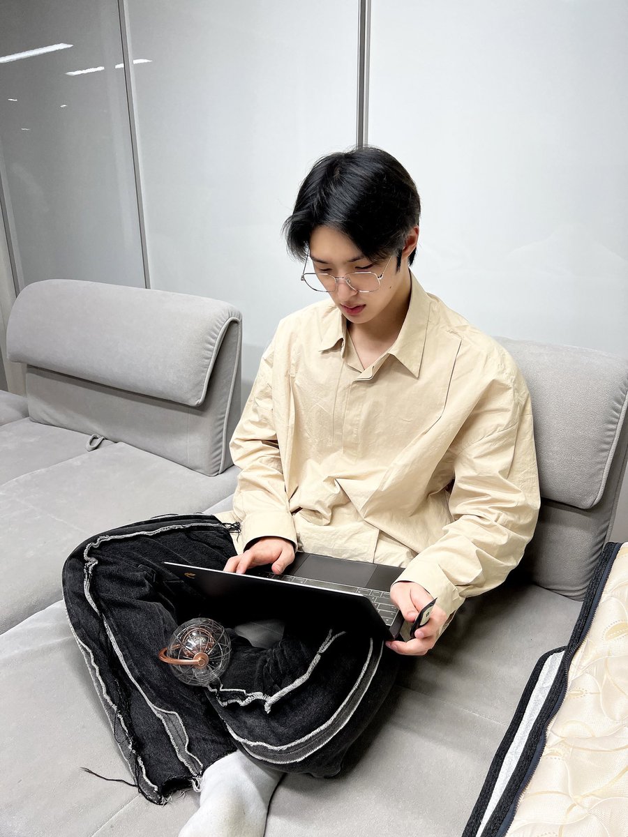this is such a cute picture of mingi. silly little guy sitting on a silly little couch with his silly little cross legged pose, with his silly little laptop and his silly little handcream with a silly little lightiny in front of him