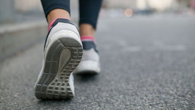 Close up photo of a person's shoes as thy are walking down a path. 