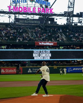 Mike Cameron, wearing a No. 44 Steelheads jersey, throws a first pitch from the pitchers mound at T-Mobile Park. Behind him, the out-of-town scoreboard reads, 