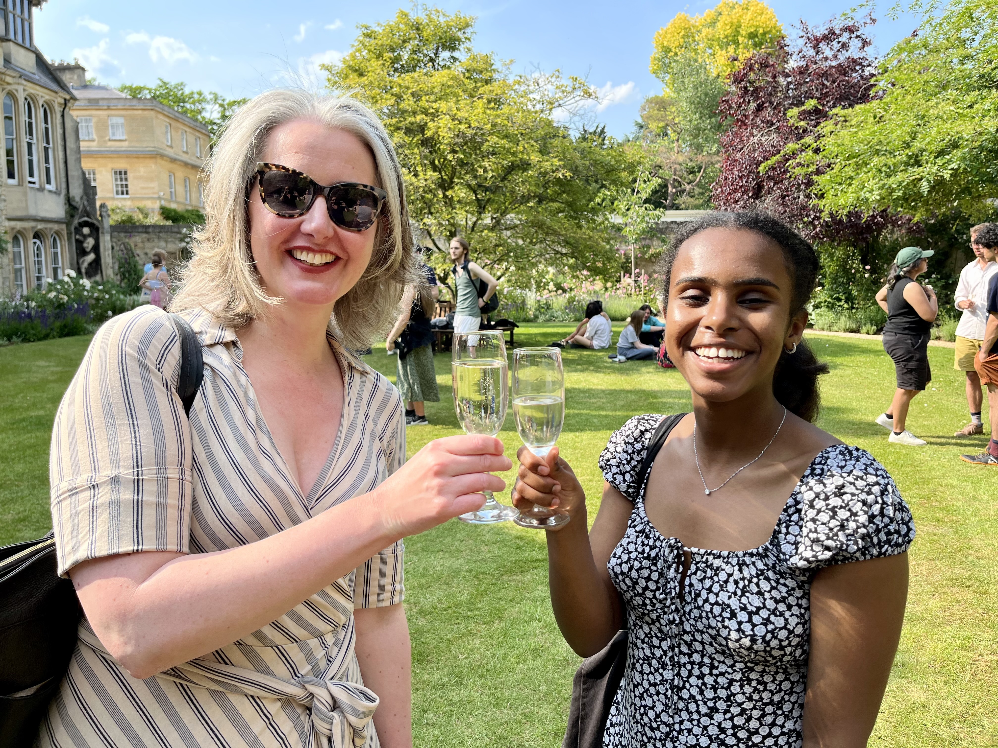 Senior Tutor Rebecca and a finalist clink champagne glasses at Trinity leavers drinks.