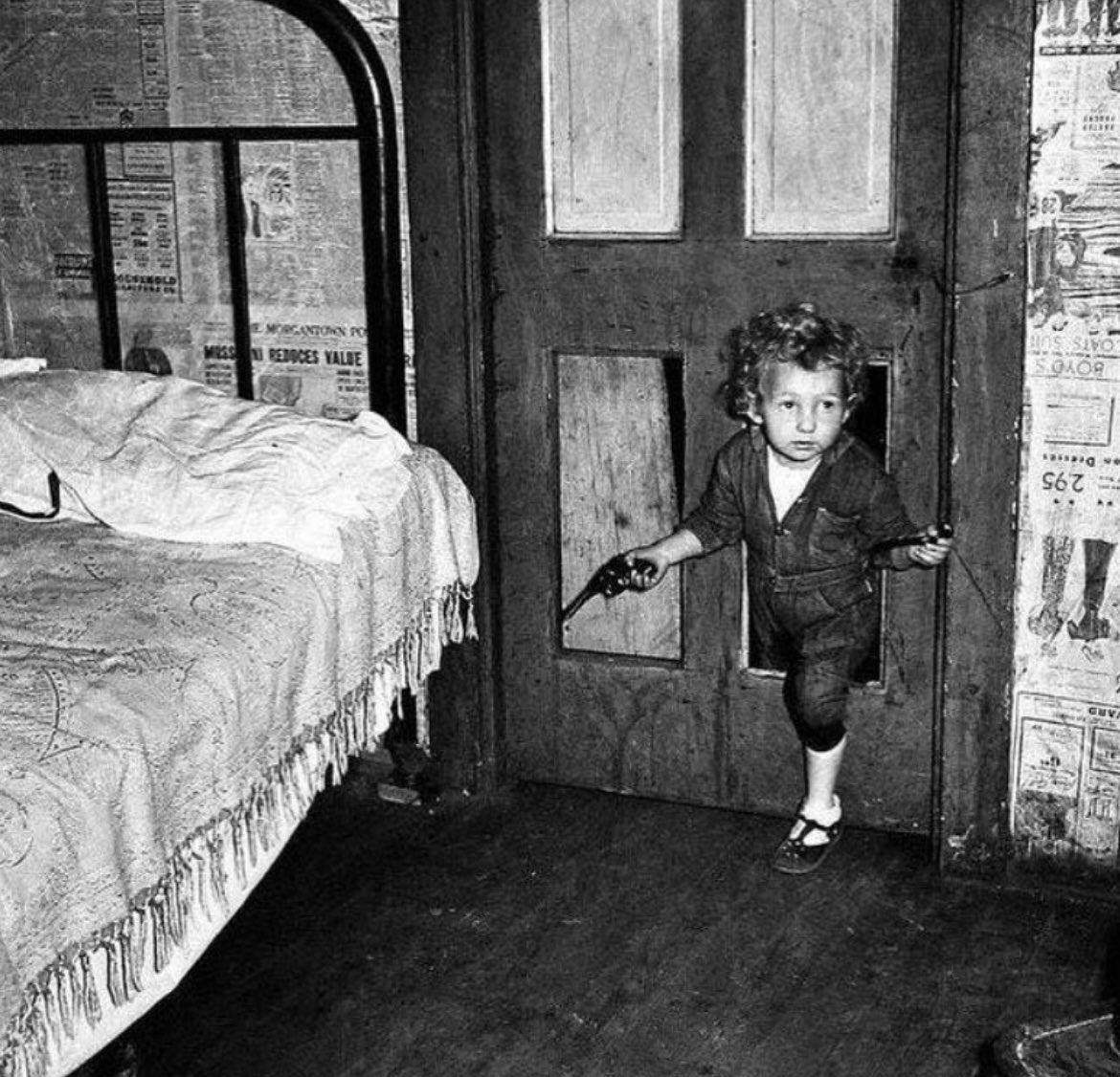 The photograph captured by Marion Post Wolcott in 1938 depicts a coal miner's child in a West Virginia home. The child is shown using a cat hole, which was a small opening in the floor used as a makeshift toilet. The image portrays the challenging living conditions and poverty