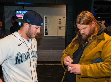 Chris Stapleton autographs a baseball for Ty France in the Mariners clubhouse.