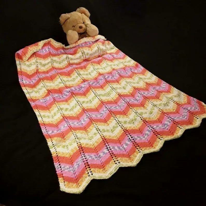 Hand knitted baby pram blanket - pink, orange, mauve, green, yellow, white chevron buff.ly/3HK4o20 #knittingtopia #etsy #knittedbabyblanket #babyblanket #newbaby #handknitted #MHHSBD #craftbizparty