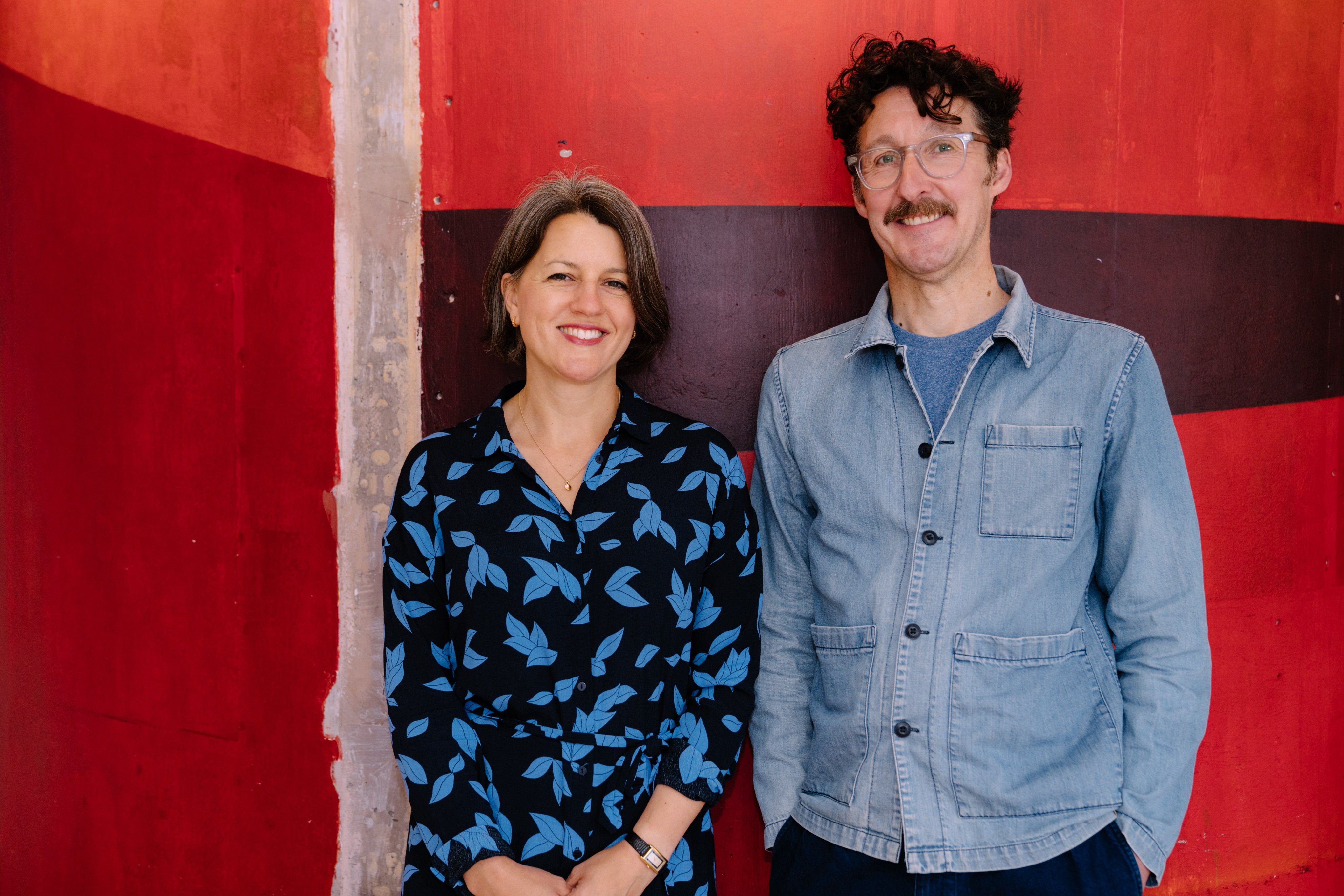 Photo of Henny Finch and Tim Sheader against a red wall