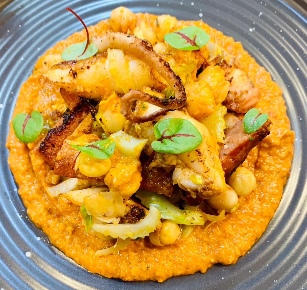 Dive into summer with this delicious dish, featuring seared octopus and andouille sausage, chipotle almond romesco, chickpeas, celery, and potato salad! Stop by and enjoy it today.