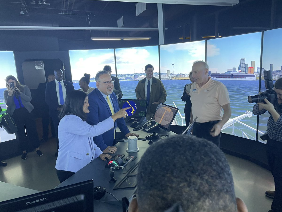 U.S. Secretary of Education Miguel Cardona and U.S. Rep. Pramila Jayapal are working together to steer a ferry into downtown Seattle.