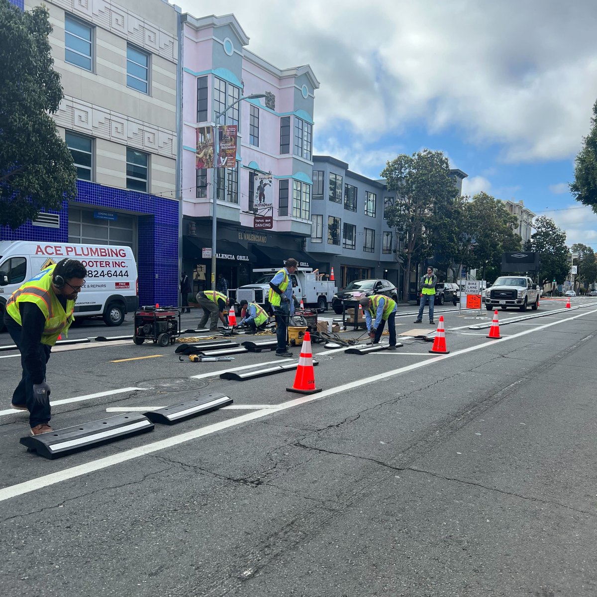 sfbike's tweet photo. Progress on Valencia's center-running bike lane is coming along – more striping, plus K-71 posts and rubber curbs are going in to prevent vehicles from entering the bike lanes. We're expecting to see these new bike lanes open sometime this summer! https://t.co/gzt2kGyA71