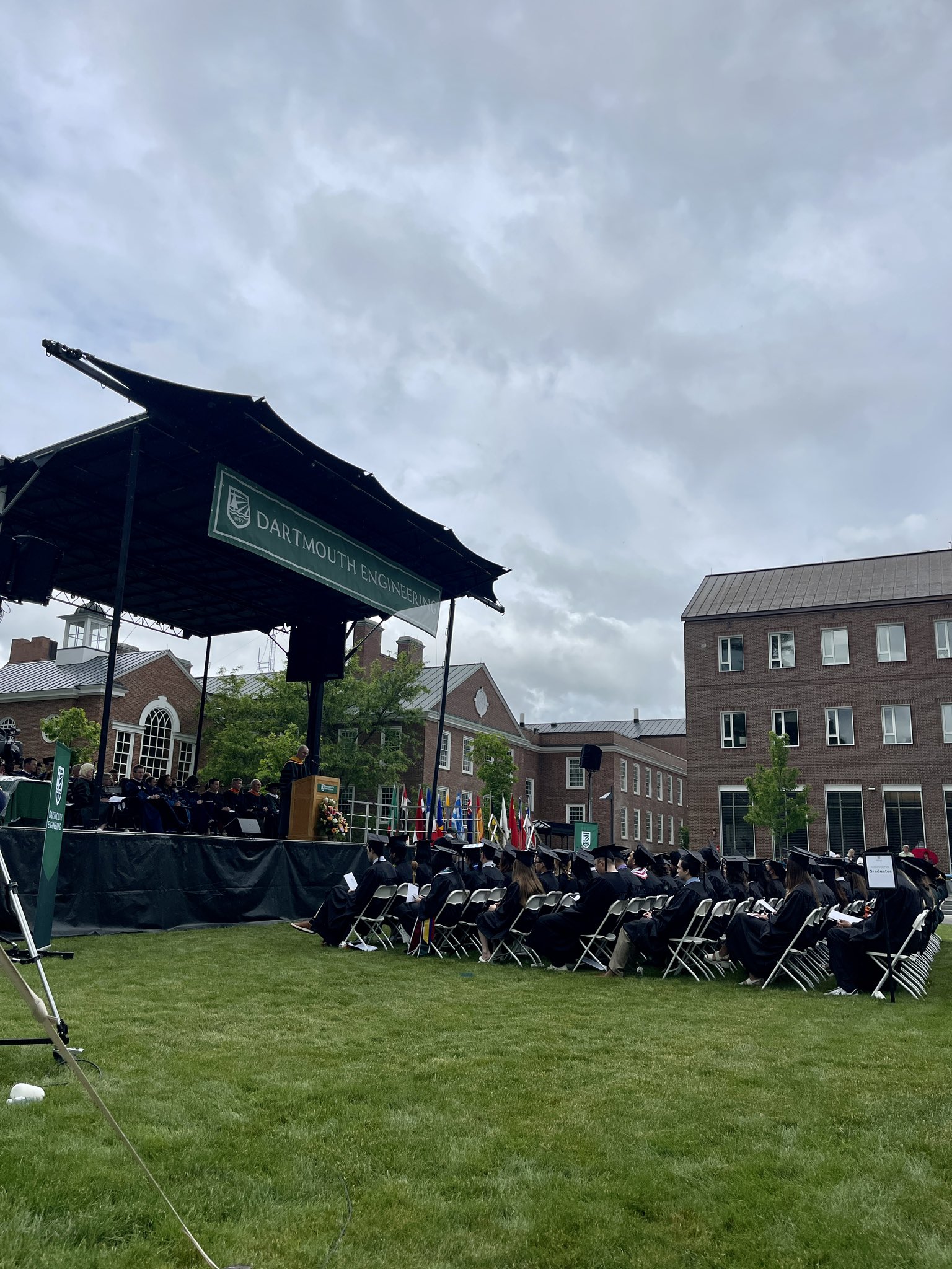 President Hanlon stands on a stage overlooking a crowd of graduates.
