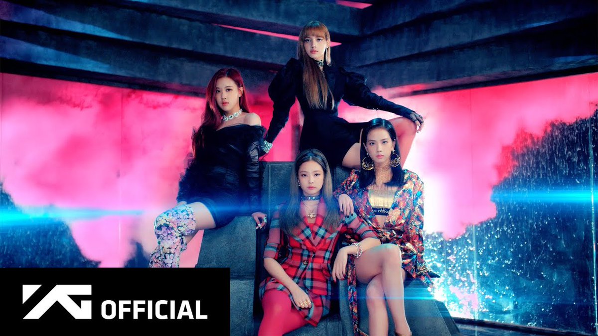 Four members of the group BLACKPINK pose together in a dramatic promotional photo with pink and blue lighting, featuring the 'YG OFFICIAL' logo.