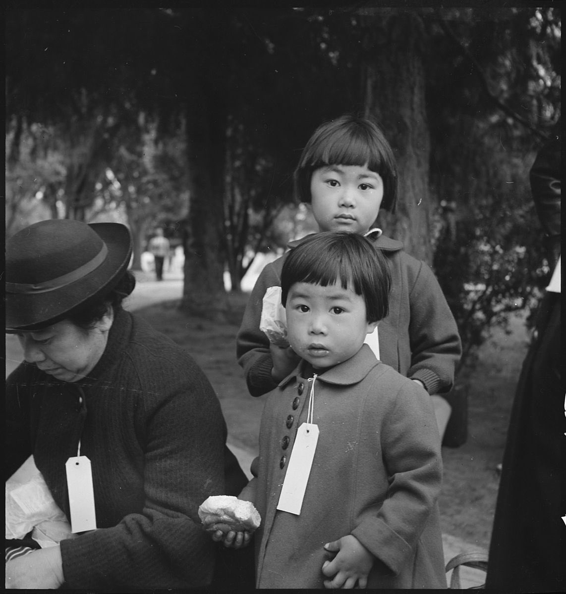 Two children of the Mochida family who, with their parents, are awaiting evacuation bus, Hayward, California, USA, 8 May 1942, by Dorothea Lange, an American documentary photographer and photojournalist