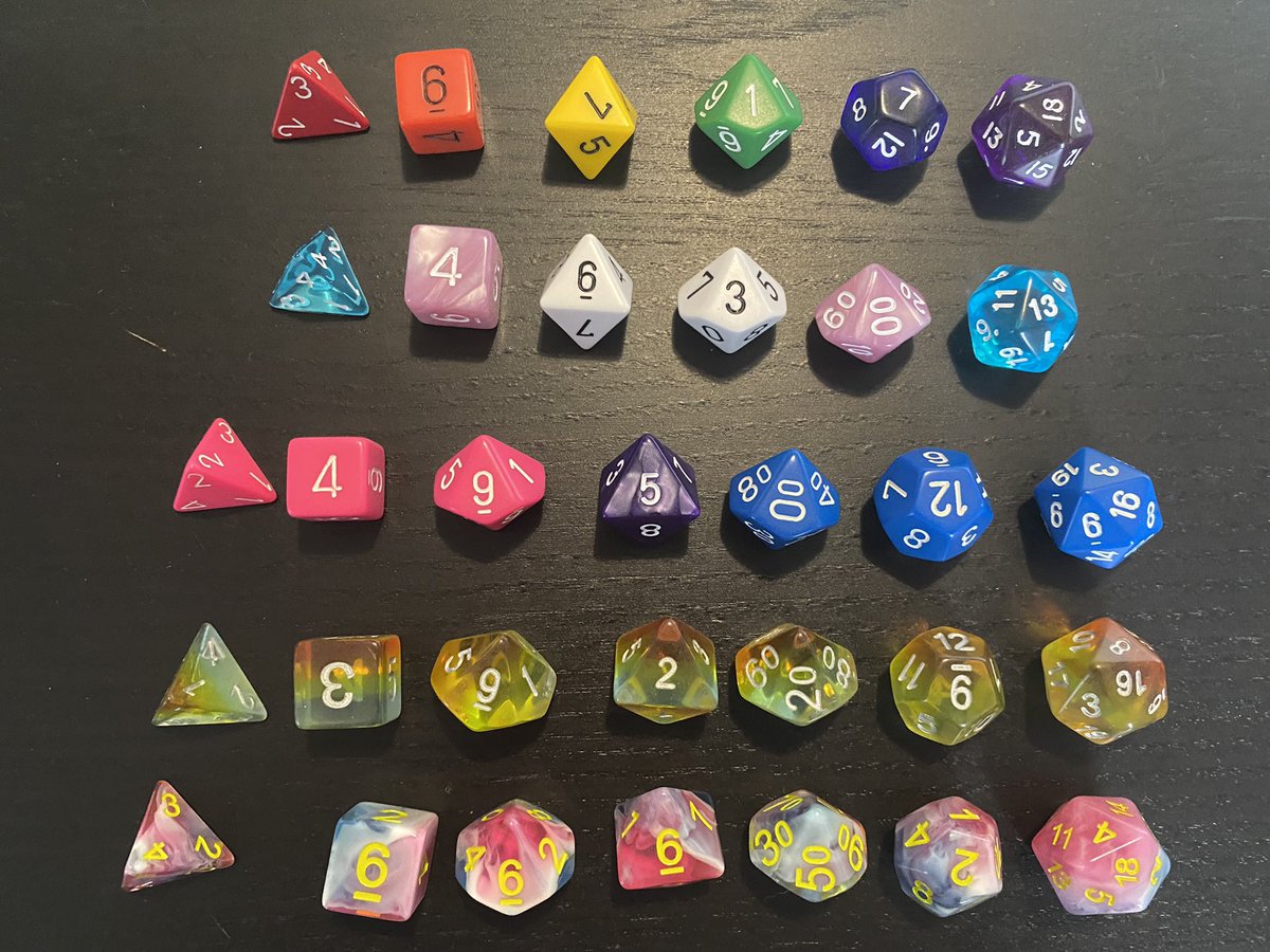 Nous avons refait nos stocks de dés. Vous trouverez toujours les monochromes arrangés aux couleurs de l’arc-en-ciel et des drapeaux transgenres et bi, mais –petite nouveauté cette année– aussi des polychromes arc-en-ciel et bleu/rose/blanc.