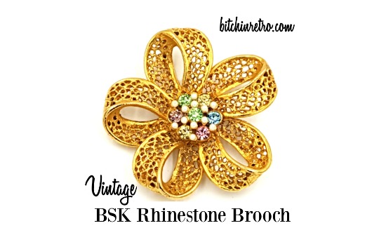 #BSK vintage filigree gold tone brooch with center "fruit salad" consisting of #pastel colored #rhinestones, and very small faux seed pearls. This #brooch has a three dimensional quality to it.

#vintage #vintagejewelry #summerstyle #bitchinretro #fashion

bitchinretro.com/products/bsk-v…